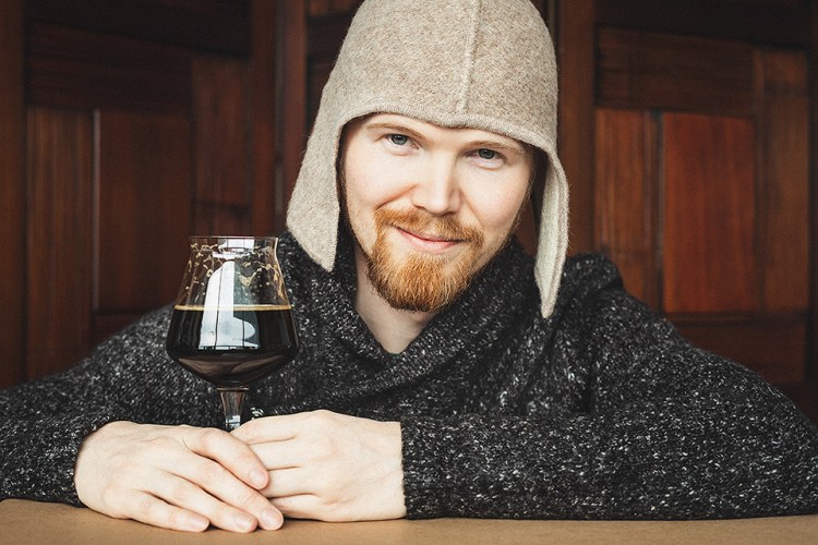 Picture of Jani Autio holding a TeKu glass filled with a rich, velvety stout.