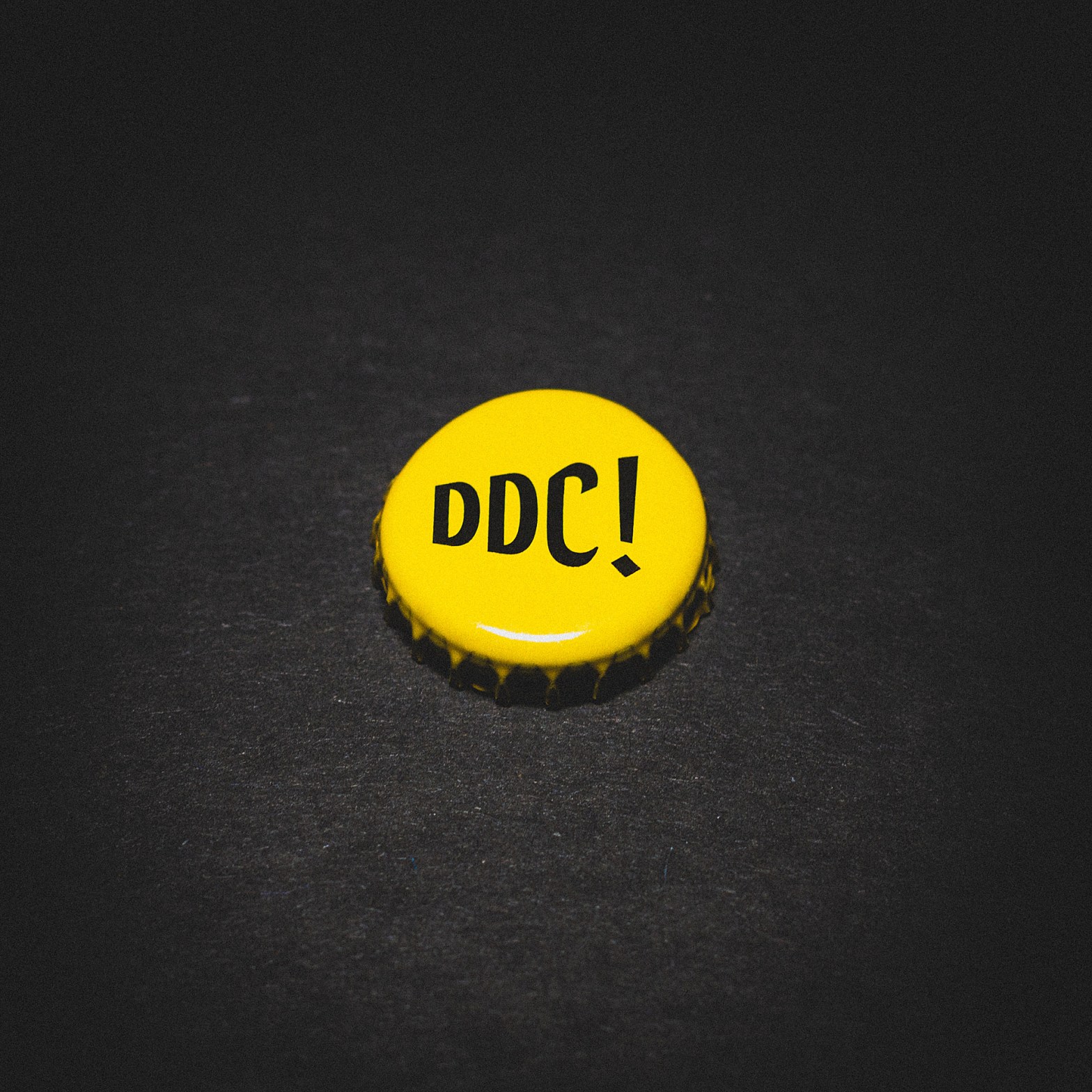Bottle cap from Dieu du Ciel!, set against a high-contrast black backdrop