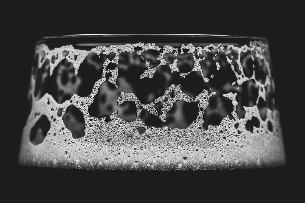 Artistic black and white macro photograph showcasing the detailed texture of lacing on a glass surface.